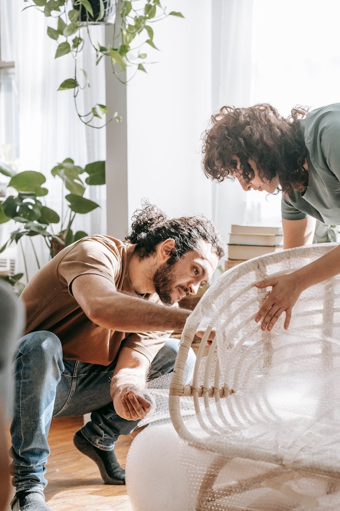 why-choose-me A couple carefully packs a wooden chair with bubble wrap in a bright, indoor setting.